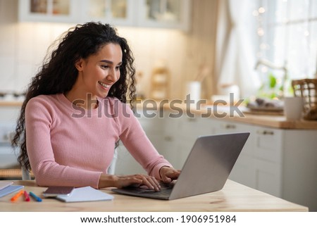 Remote Work. Beautiful Young Freelancer Lady Working With Laptop In Kitchen, Happy Millennial Woman Using Computer At Home, Sitting At Table In Cozy Interior, Enjoying Online Job, Free Space