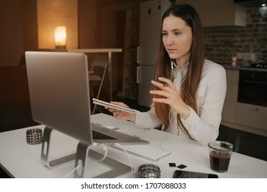  Remote work. A brunette woman with headphones working remotely online on her laptop. A girl actively discussing problems with her colleagues through a video call at her cozy home workplace. - Shutterstock ID 1707088033