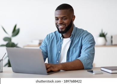 Remote Work. Handsome Black Freelancer Guy Working On Laptop At Home Office, Sitting At Desk With Computer, Smiling African American Man Looking At Device Screen, Enjoying Freelance Job, Copy Space