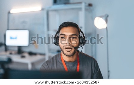 Remote work online technical support concept. Portrait young adult indian man wearing headset typing keyboard working in office. It support business customer service technology.