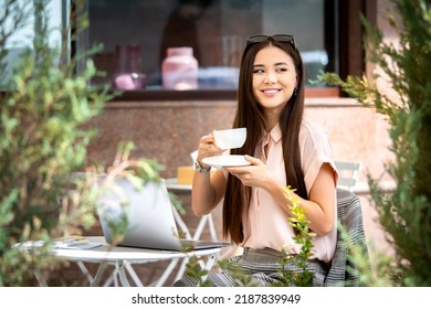 Remote Work Outside The Office, Outdoor Workplace. Beautiful Young Asian Woman Taking Rest From The Work With A Cup Of Coffee. Autumn Mood. Infusion Into The Business Process After Summer Holidays.