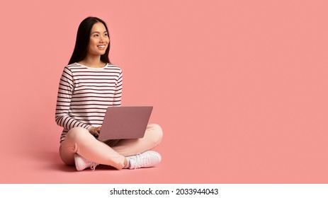 Remote Work. Portrait Of Smiling Young Asian Female Sitting With Laptop Computer On Lap And Looking Aside At Copy Space On Pink Studio Background, Happy Korean Woman Enjoying Distance Job, Panorama