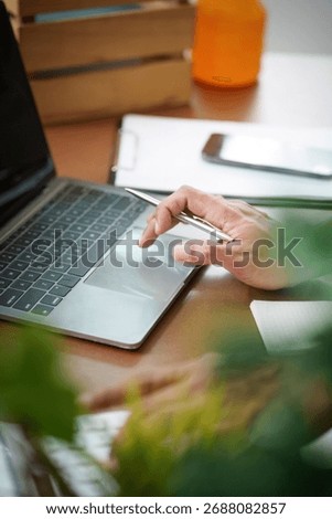 Remote Work. Professional using laptop and pen for productivity in a cozy workspace.