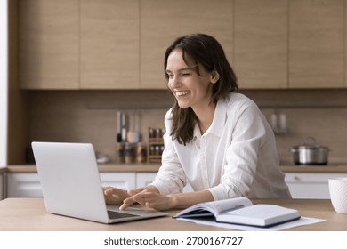 Remote work or study. Beautiful smiling young female student freelancer working learning at distance from home office search information online browse websites check email review data using notebook