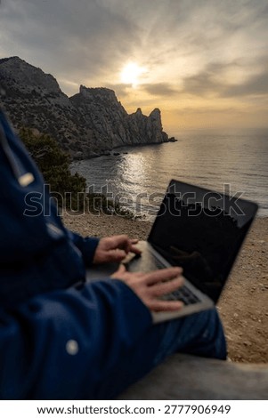 Remote work sunset laptop worker using keyboard outdoors on rugged cliff overlooking ocean