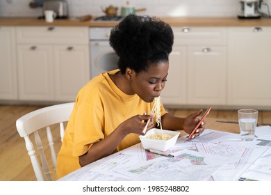 Remote worker businesswoman has lunch in hurry work from home. Freelancer designer or architect african american female eating and chatting on smart phone sit at kitchen table with project blueprints. - Powered by Shutterstock