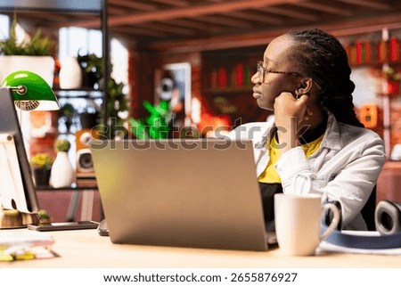 Remote worker pausing work done on laptop at home to pensive thinking. African american teleworker in apartment feeling bored by repetitive tasks, stopping work on notebook to daydream