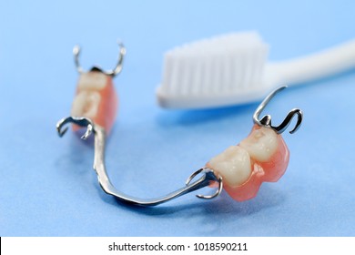 Removable partial denture cleaning with blur toothbrush background.