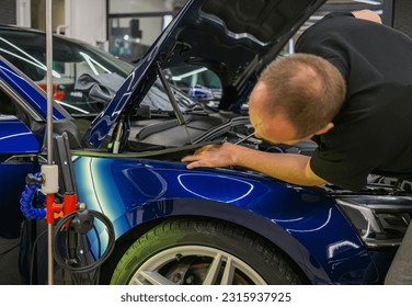 Removal of dents without painting. PDR technology for car body repair. PDR. The mechanic at the auto shop with tools to repair dents in car body. Body repair. - Powered by Shutterstock