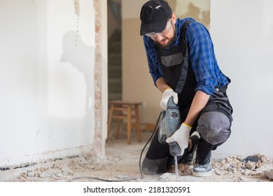 Removal of old floor during renovation of apartment. The idea of working by hand. Close-up of chisel from demolition hammer, fragments of ceramic tiles, dust. Male worker puts all strength into work.