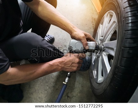 Removing car mechanic to repair the leaky tire car wheels.Mechanic changing a car tire on a vehicle a hoist using an electric drill to loosen the bolts .concept of service or replacement.