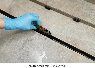 Removing Clogged Shower Drain, Gloved Hand Removes Hair Close-up