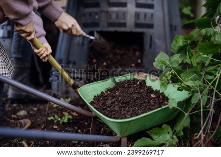 Removing compost from a composter in garden. Concept of composting and sustainable organic gardening.