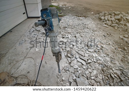 Removing concrete floor with jackhammer tool. Concrete rubble debris on construction site. Destruction of old concrete. Construction tools, jackhammer on the destroyed floor. Electric jackhammer.