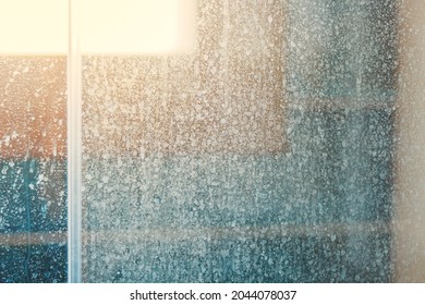 Removing hard water stains and deposits in bathroom. Stains drops on glass shower doors. Cleaning bathroom concept. - Shutterstock ID 2044078037