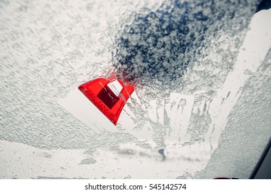 Removing Ice From The Car Windshield With The Red Scraper