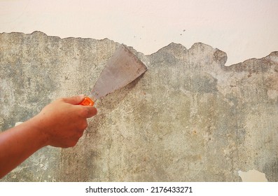 Removing Old Paint From The Old Wall By Hand With A Metal Spatula. Painting Preparation At Home