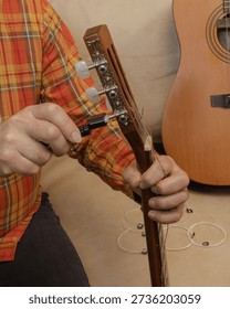 Removing old strings from a classical guitar using a string winder