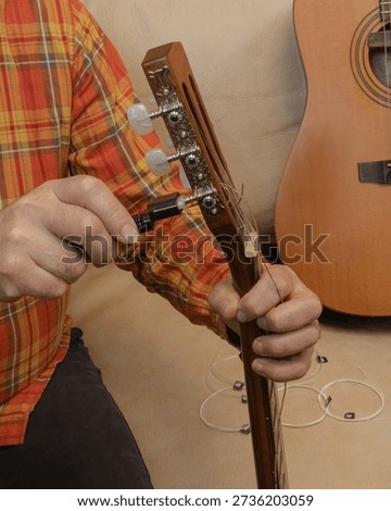 Removing old strings from a classical guitar using a string winder