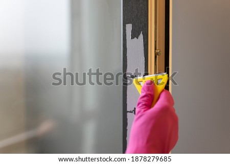 Removing protective tape from the window frame with scraper