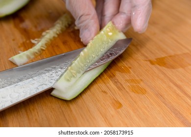 Removing The Seed Pit And Core Of A Cucumber With A Sharp Stainless Knife While Wearing Plastic Gloves.