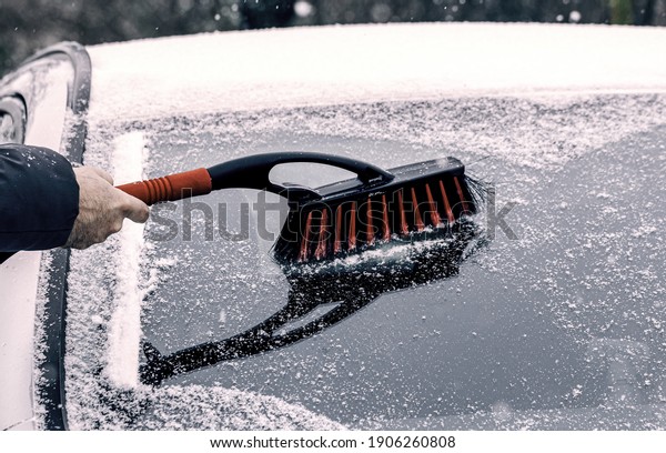 Removing\
snow from car. Clean car window in winter from snow, winter brush\
and scraper clearing car after snow\
blizzard.