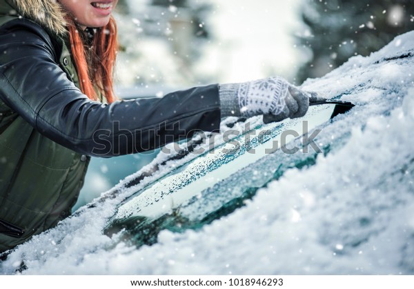 Removing snow from car windshield.  Clean car\
window in winter from\
snow.