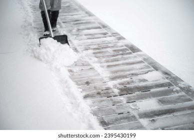 removing the snow from a hard floor of the patio - Shutterstock ID 2395430199
