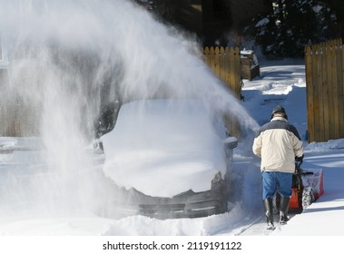 removing snow on the driveway of the house by snow blower