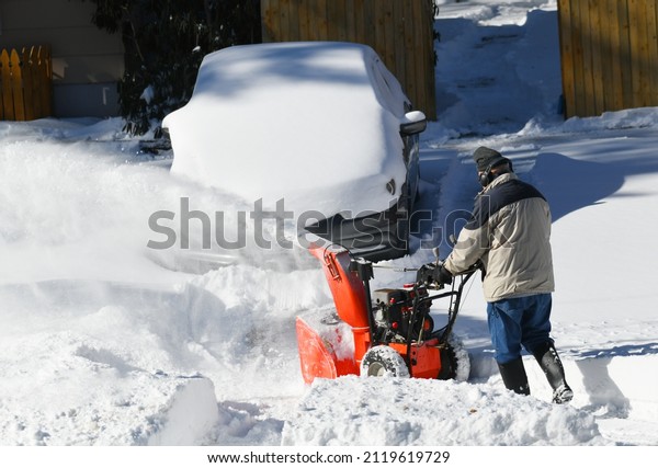 removing\
snow on the driveway of the house by snow\
blower