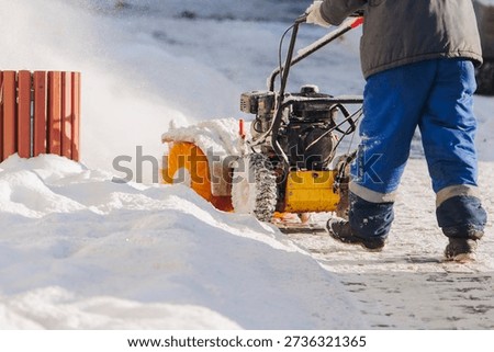 Removing snow with portable blower machine during winter, worker with gas snow blower removal in the streets after snowfall, clearing residential sidewalk driveway with snow sweeper, snowplow machine