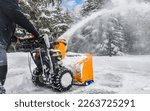 Removing snow with a snowblower on snowy road. Snow storm service or maintenance concept.