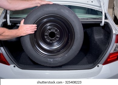 Removing A Spare Tire From The Trunk Of A Car