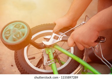 Removing The Training Wheels. Father Repairing His Kids Bicycle.