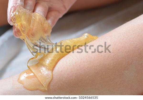 Removing\
unnecessary hair on the legs. Procedure sugaring in a beauty salon.\
Sugar depilation. Depilatory sugar\
paste