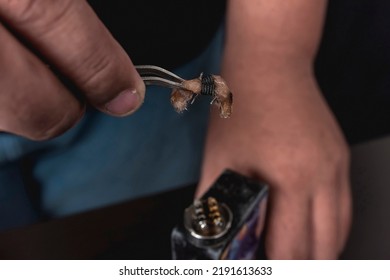 Removing The Used Cotton Wick And Coil With A Pair Of Tweezers. Box Mod Vape Maintenance.