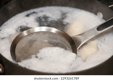 Removing the white foam know as chicken scum from the surface of stock pot when boiling chicken.