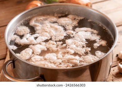 Retirar la espuma blanca conocida como escoria de pollo de la superficie de la olla de caldo cuando hierve el pollo. Caldo óseo