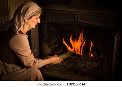 Renaissance old master portrait of a peasant woman adding wood to a burning fire
