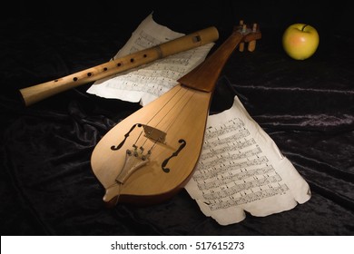 Renaissance violin (rebec) and alto recorder in a dark room with musical score