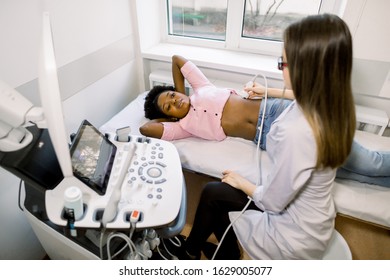 Renal Ultrasound Examination Of Kidneys. Hospital Female Doctor Examines A Young African Woman With Ultrasound.