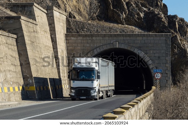 Renault semi-truck transporting goods on the street.\
White truck with container without logo carrying freight on the\
mountain road, at the exit of a tunnel. Severin, Romania, October\
25, 2021