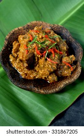 Rendang - spicy delicious meat dish cooked with herbs, spices and coconut milk served on black plate 