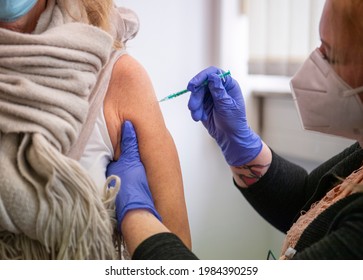 RENDSBURG, GERMANY - MARCH 3, 2021: 60 Year Old Woman Is Vaccinated Against Covid-19 With Astra-Zeneca Vaccine By A Young Lady Wearing A Face Mask And Blue Gloves