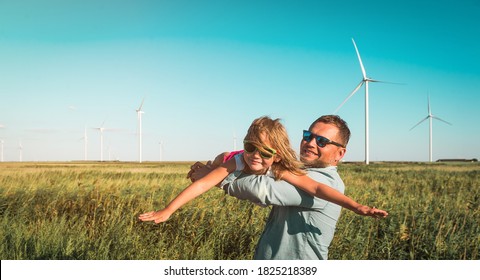 Renewable energies and sustainable resources - wind mills. Father and little kid daughter playing on field with wind farm. Child in sunglasses with hands like an plane - Shutterstock ID 1825218389