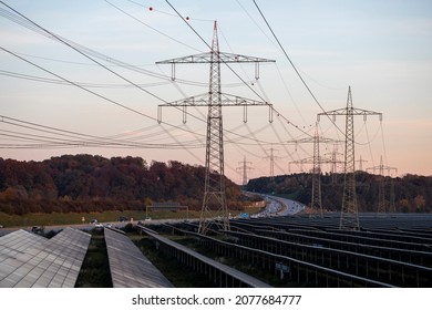 Renewable Energy, Large Field Of Solar Panels, Solar Panels And High Voltage Electricity Pylons Next To A Highway 