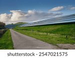 Renewable Energy in the Netherlands: Large solar panel park on a re-purposed landfill showing renewable energy integration with green landscape under a blue sky with scattered clouds.