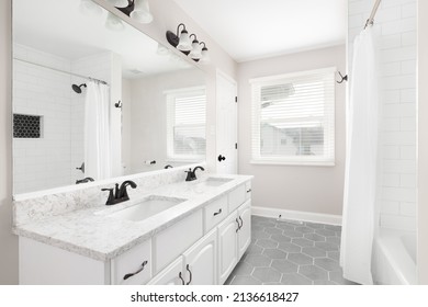 A Renovated Bathroom With A White Vanity, Grey Hexagon Tiled Floor, Marble Countertop, And A Shower With White Subway Tiles.