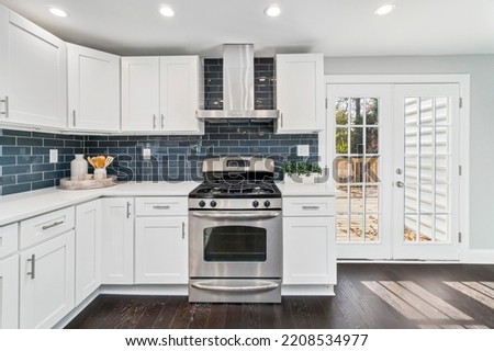 Renovated kitchen with stainless steel appliances, white cabinets and subway glass tile backsplash in single family residential property.