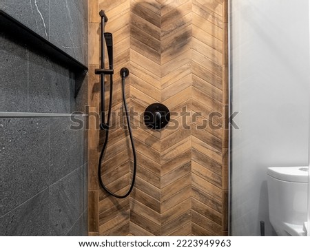 Renovated modern bathroom with walk-in shower. Dark (Black Grey) tile with herringbone wood pattern design tiled wall with niche.
